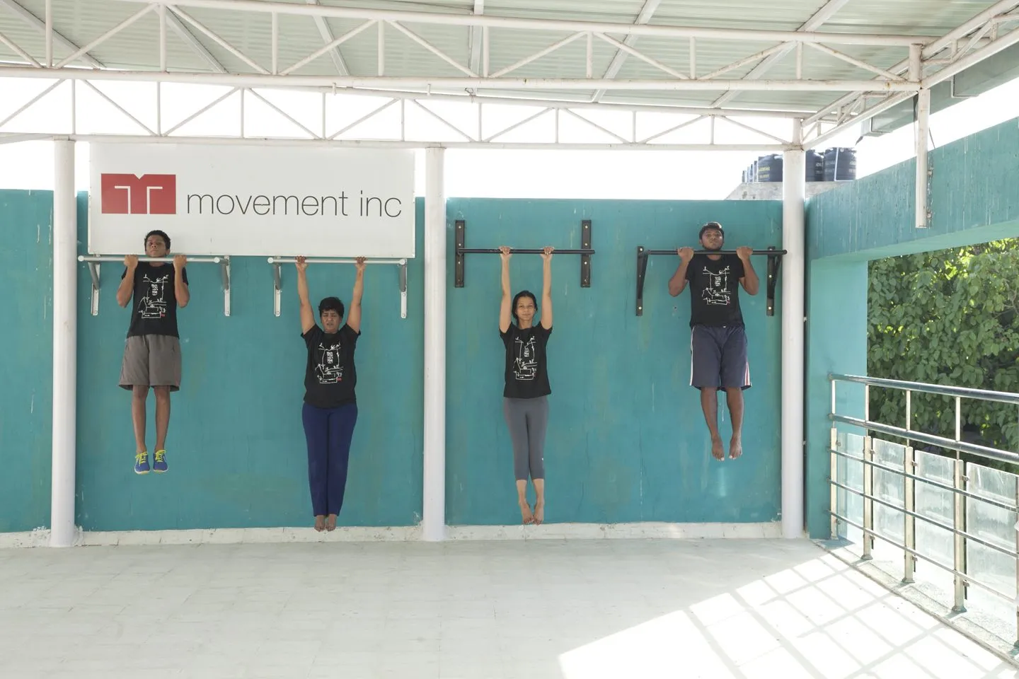 Four wall mounted pull up bars at staggered heights on the gym's teal wall